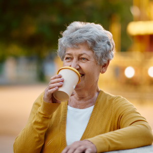 Elderly woman drinking a takeout coffee