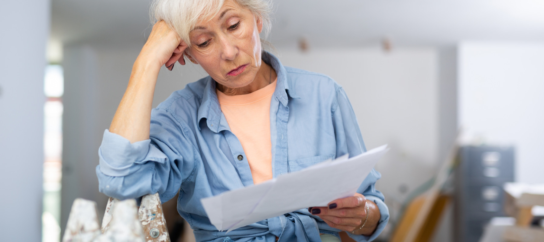 Senior woman stressed looking at home maintenance costs.