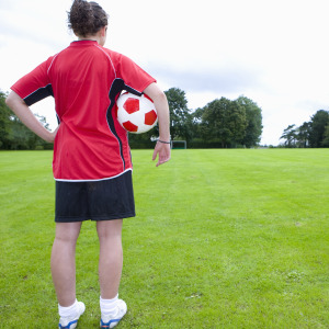 girl with soccer ball empty field