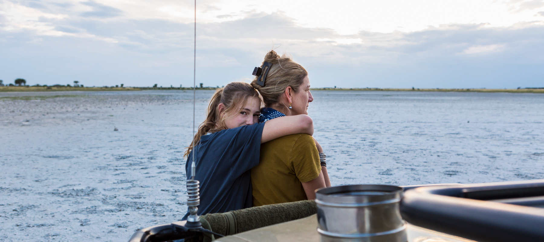 Mother and daughter seen from behind, with daughter hugging her mom.