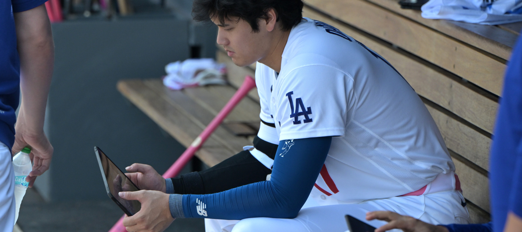 Shohei Ohtani of the Los Angeles Dodgers checks an iPad in the dugout