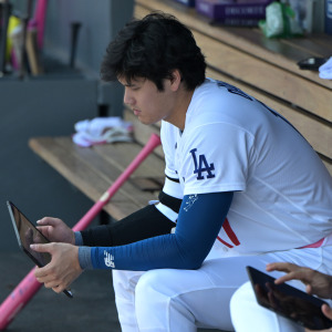 Shohei Ohtani of the Los Angeles Dodgers checks an iPad in the dugout
