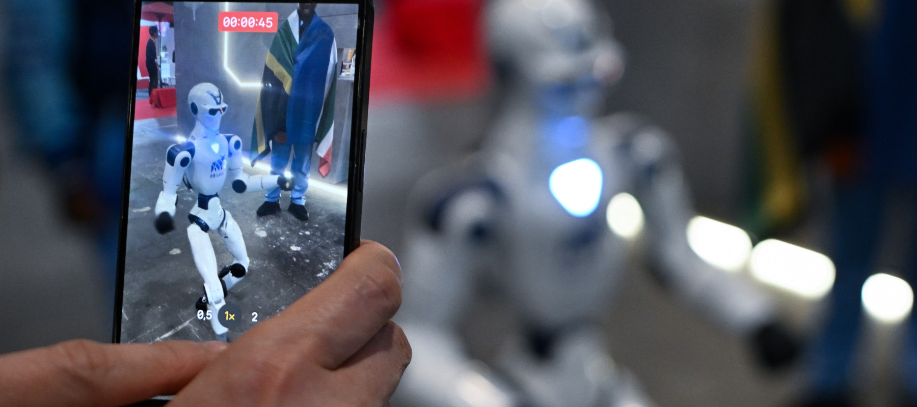 A participant records a video of a walking robot at AI for Good Global Summit in Geneva, Switzerland.