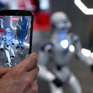 A participant records a video of a walking robot at AI for Good Global Summit in Geneva, Switzerland.