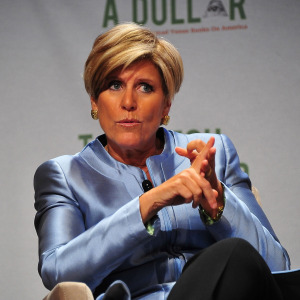Suze Orman speaks on stage, looking serious and counting on her fingers.