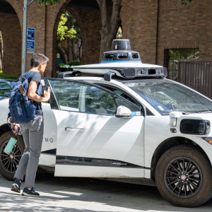 Pedestrians exit a parked Waymo self-driving car in front of Google's San Francisco headquarters.