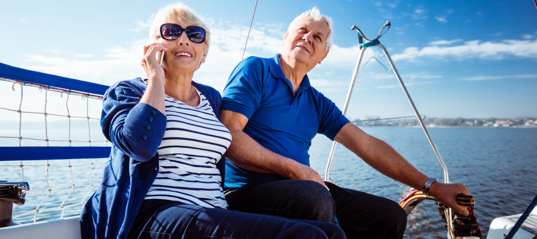 A wealthy couple dressed in blue relax on a boat on a beautiful summer's day.