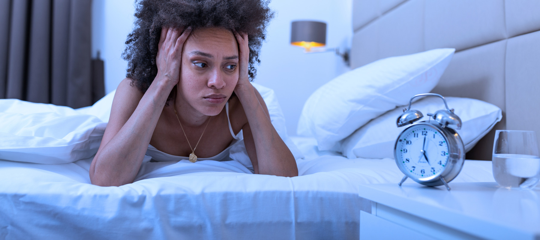 A woman struggles to fall asleep in her bed.