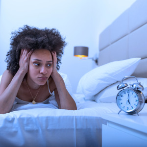 A woman struggles to fall asleep in her bed.