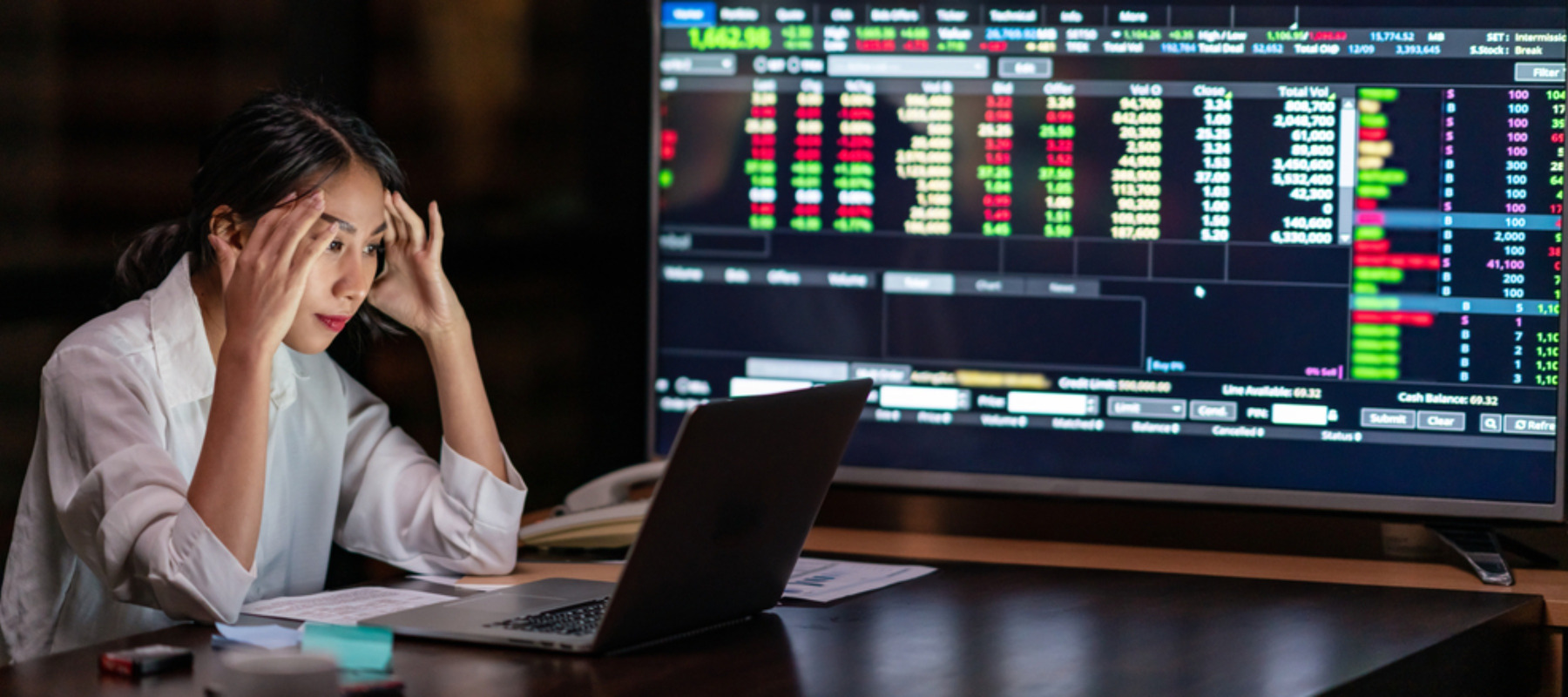 Photo of a woman looking upset with a trading terminal in the background