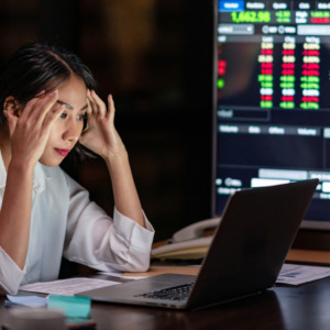 Photo of a woman looking upset with a trading terminal in the background