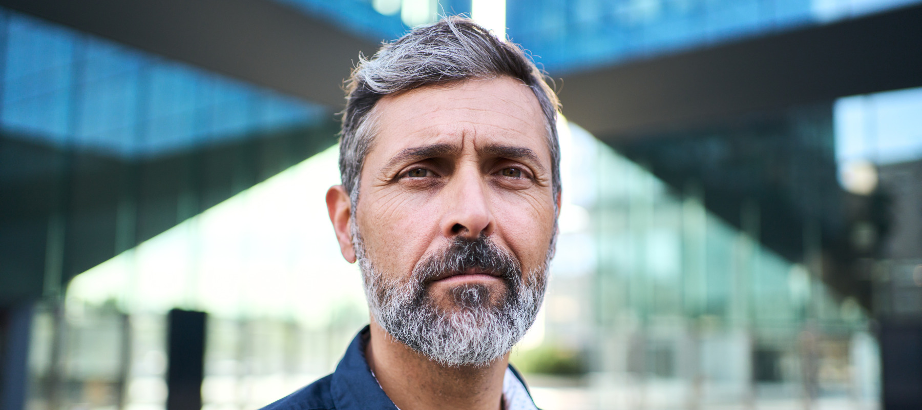 Man with salt-and-pepper hair looks directly at the camera, appears serious.