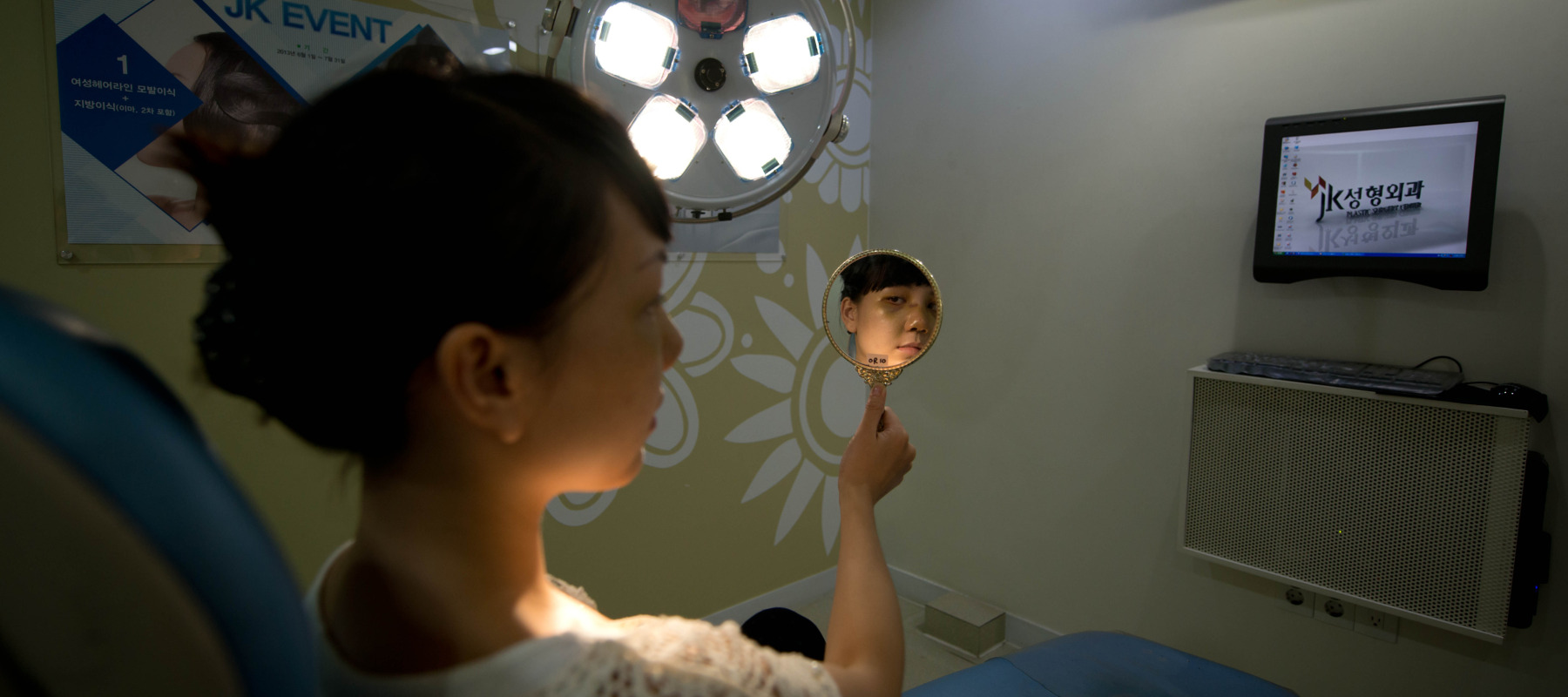 Woman looks into a mirror while sitting in a chair at a doctor's office.