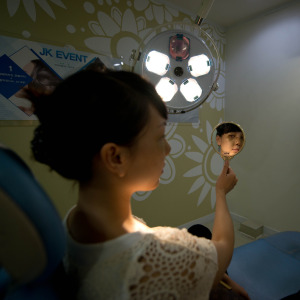 Woman looks into a mirror while sitting in a chair at a doctor's office.