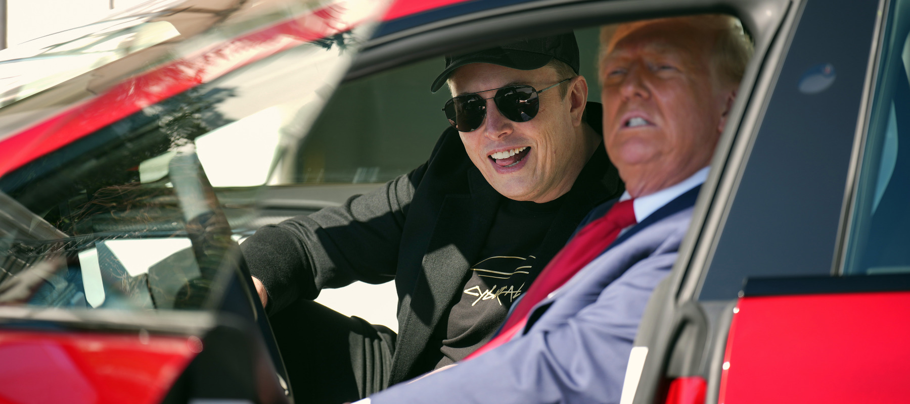 Elon Musk and President Trump sit inside a Tesla vehicle.