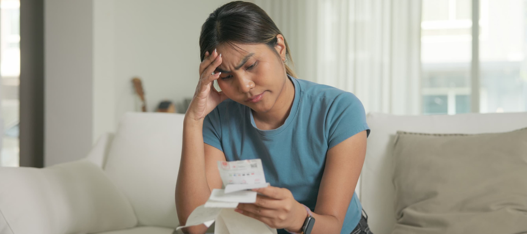 A photo of a millennial woman stressed, reviewing receipts
