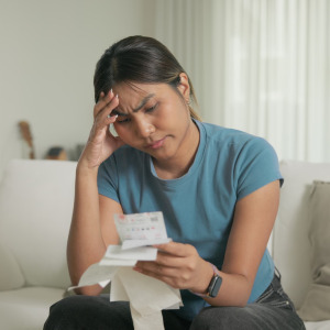A photo of a millennial woman stressed, reviewing receipts