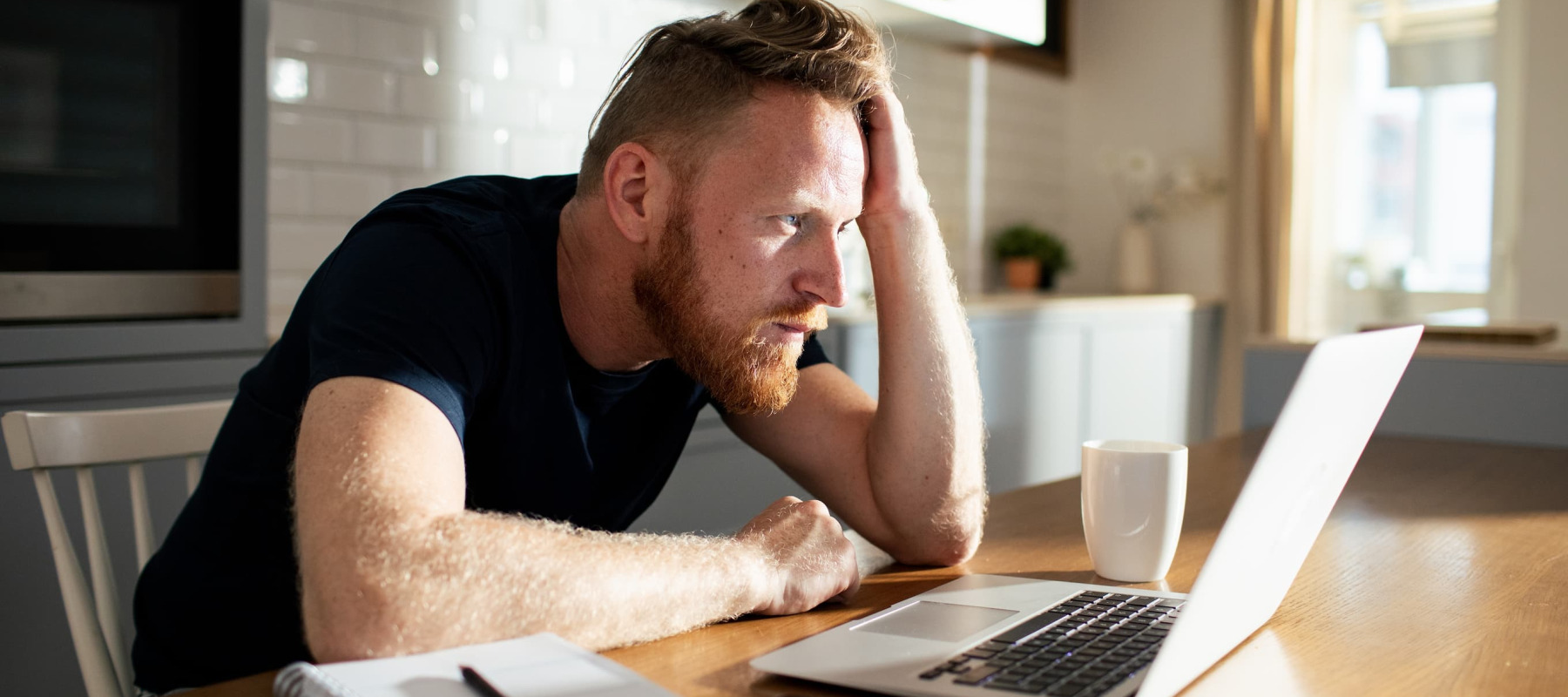 A photo of a man reviewing finances on his laptop