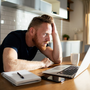 A photo of a man reviewing finances on his laptop