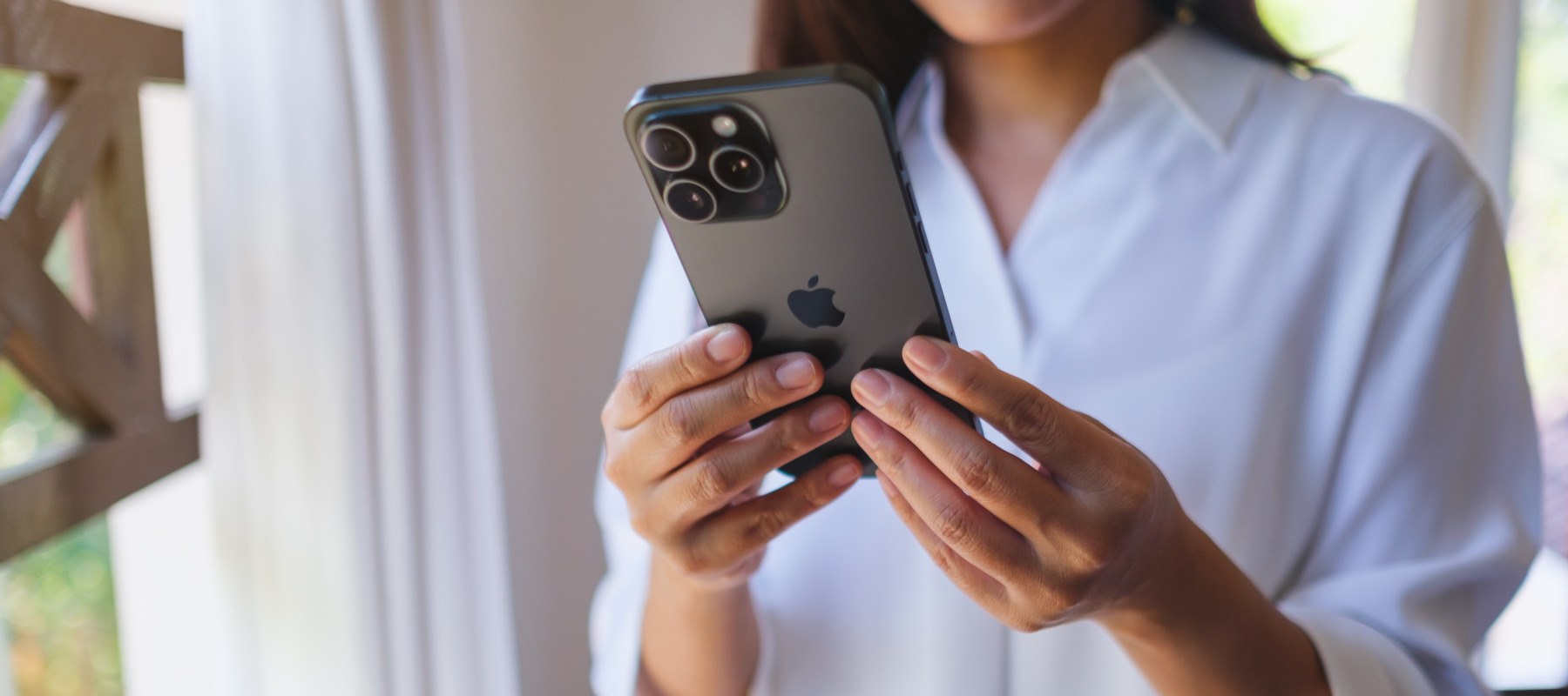 A woman holding and using an iPhone 15 Pro Max