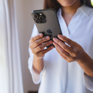 A woman holding and using an iPhone 15 Pro Max