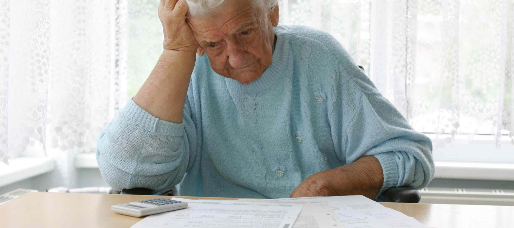 Elderly woman looks stressed as she looks over her finances