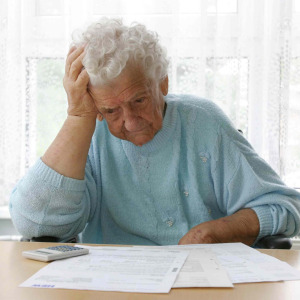 Elderly woman looks stressed as she looks over her finances