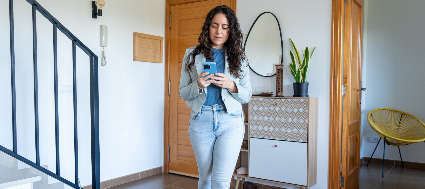Woman looking at her phone while walking through home for sale