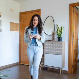 Woman looking at her phone while walking through home for sale