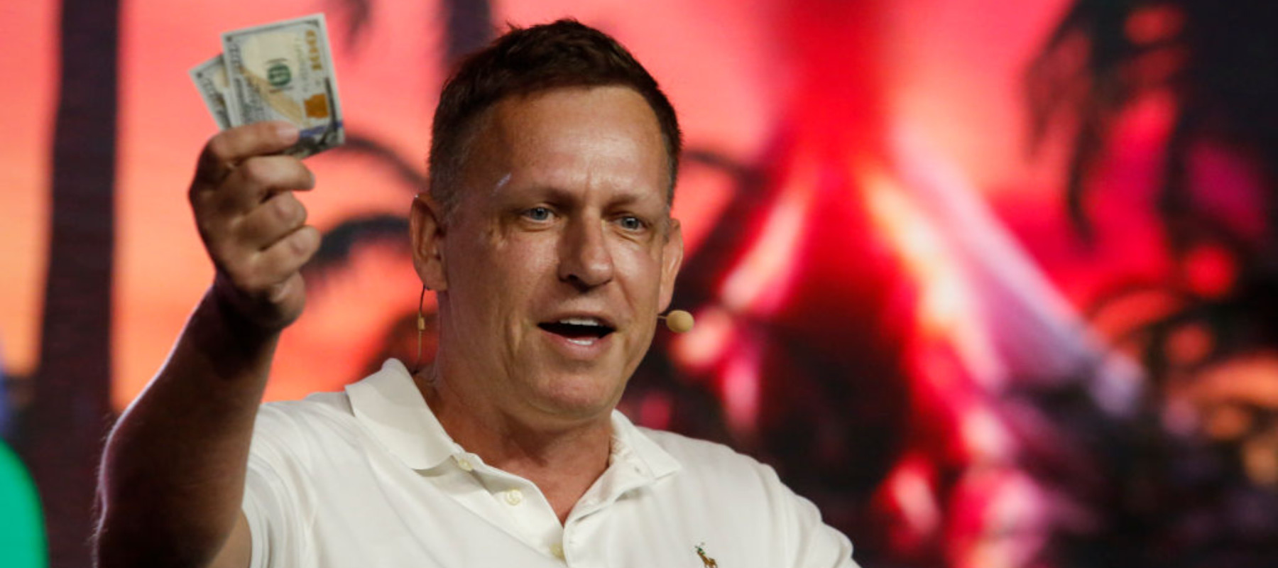Peter Thiel, co-founder of PayPal, Palantir Technologies and Founders Fund, holds hundred dollar bills as he speaks during the Bitcoin 2022 Conference at Miami Beach Convention Center.
