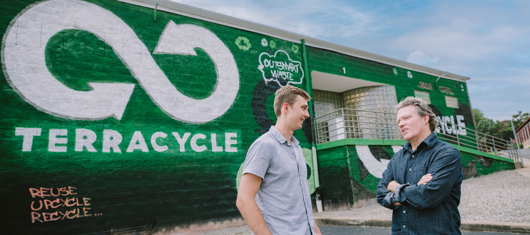 Two TerraCycle employees stand outside the company's building.