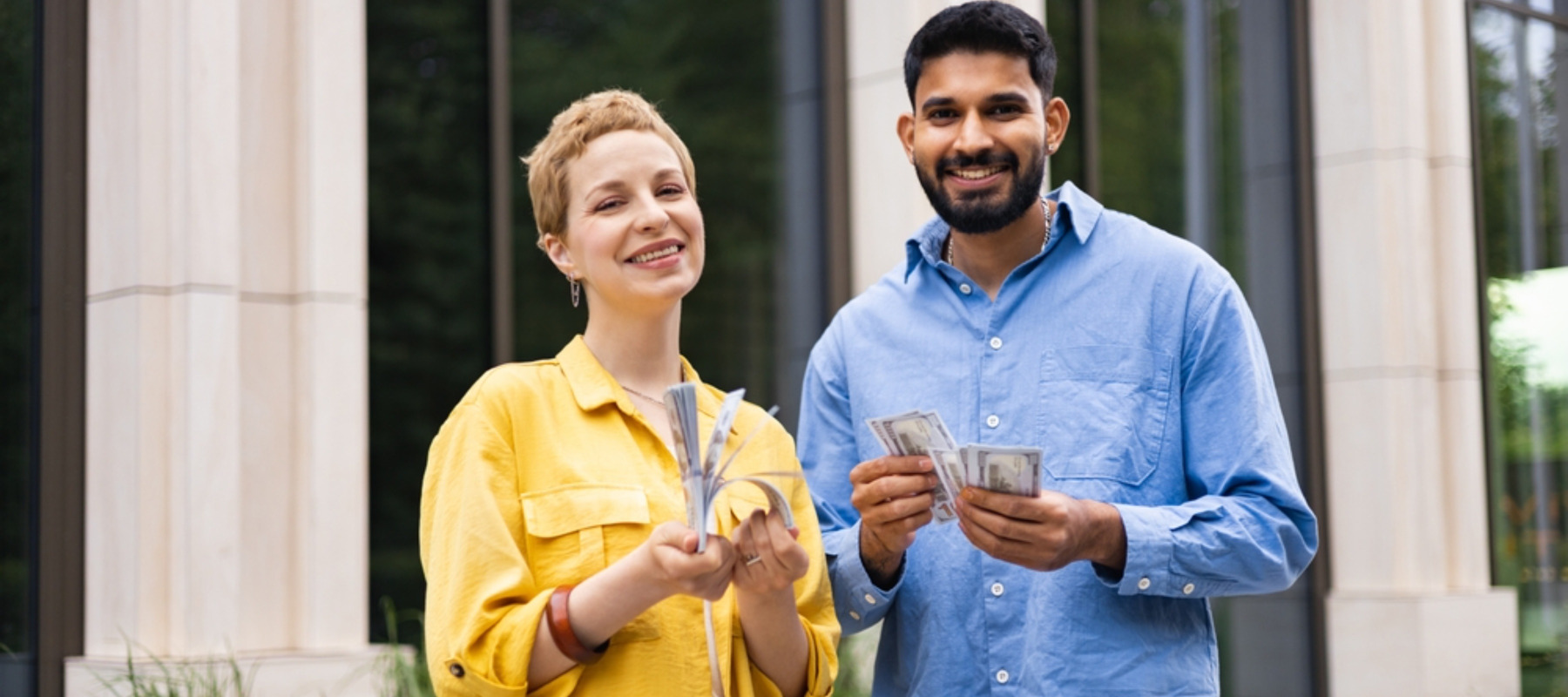 Photo of a couple standing outside smiling and holding money