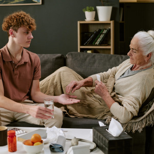Young man giving medicine to elderly relative
