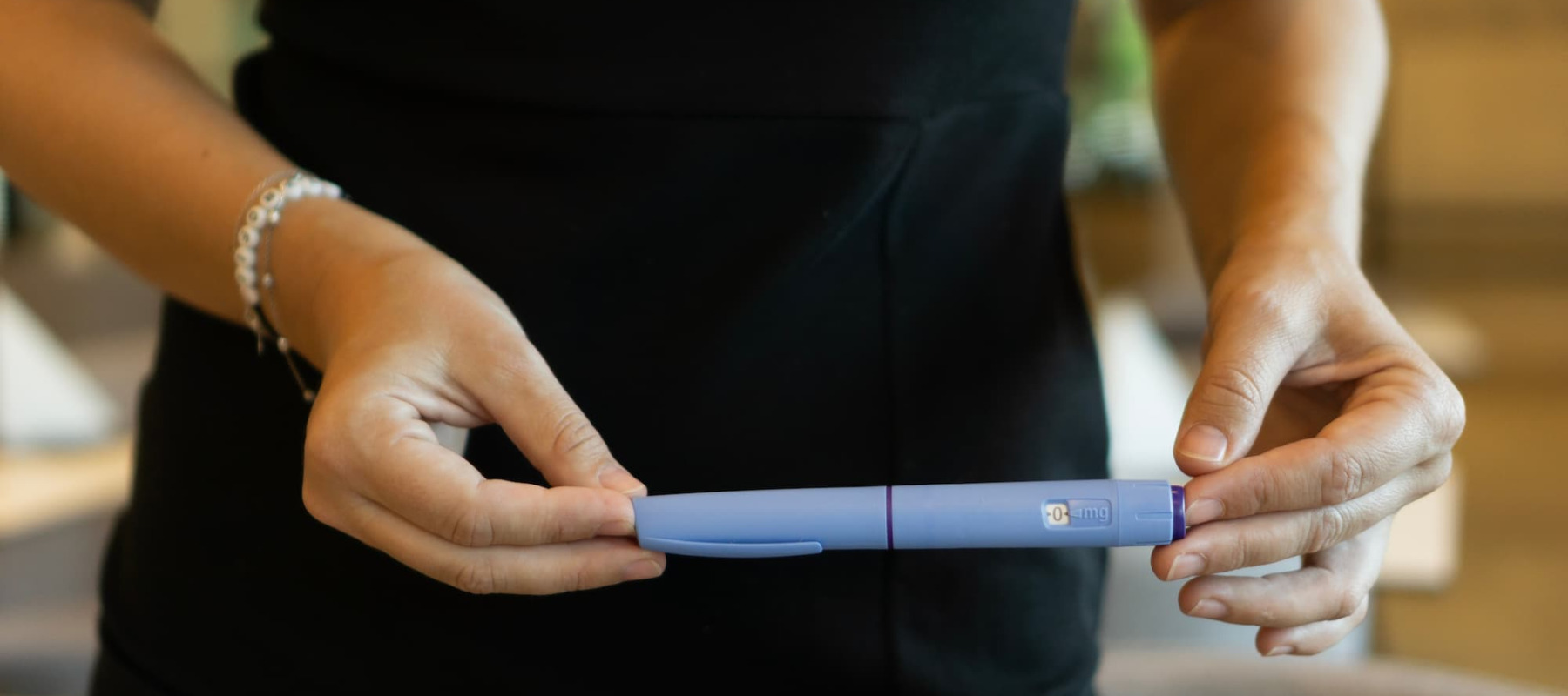 A photo of a woman holding a GLP-1 pen
