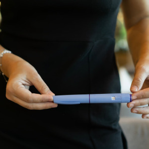 A photo of a woman holding a GLP-1 pen