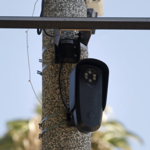 A Flock Safety camera is shown mounted to a light pole. The technology has drawn criticism from privacy advocates.
