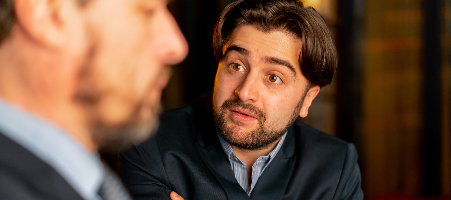 Two men seen speaking in a heated exchange, one gesturing with his hands. They're clearly upset.