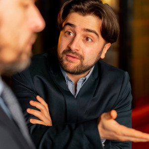 Two men seen speaking in a heated exchange, one gesturing with his hands. They're clearly upset.