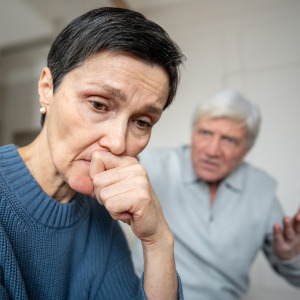 Woman looks very concerned in the foreground, while angry man behind her gesticulates.