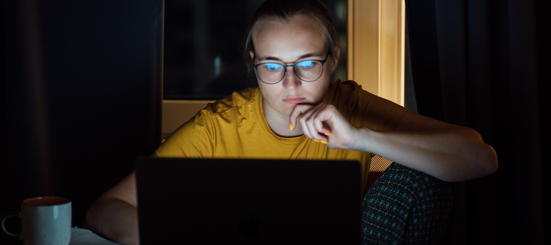 Young woman looking at computer in dark room