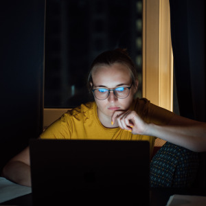 Young woman looking at computer in dark room