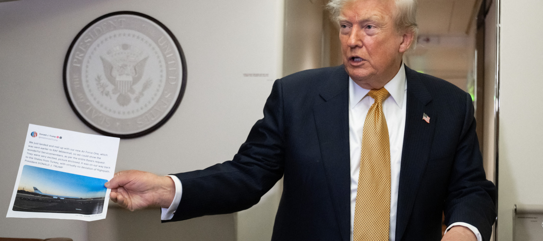 The president holds up a printed-out Truth Social post on Air Force One.
