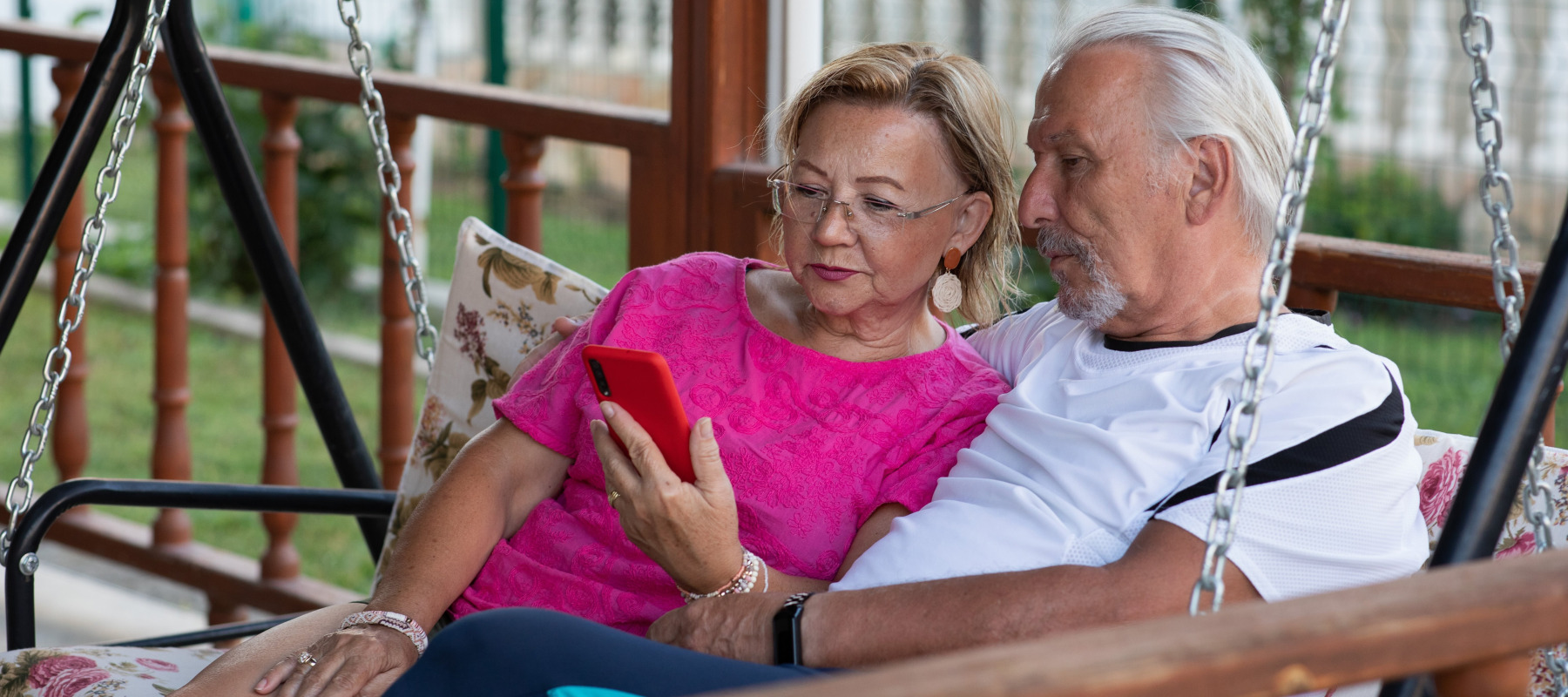 Retired couple looking at smartphone together in their backyard
