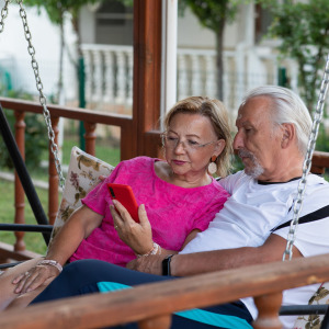 Retired couple looking at smartphone together in their backyard