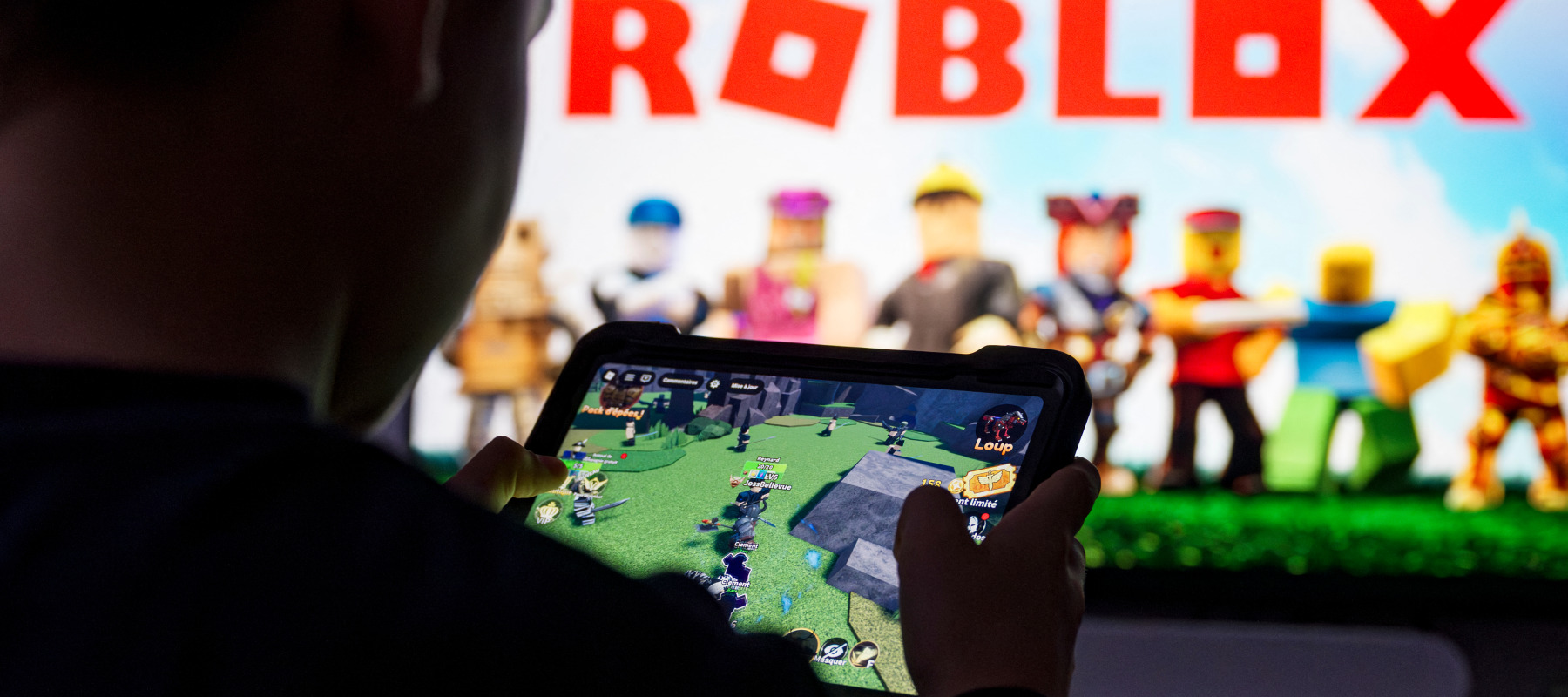 A child poses as he plays a video game on a tablet on Roblox.
