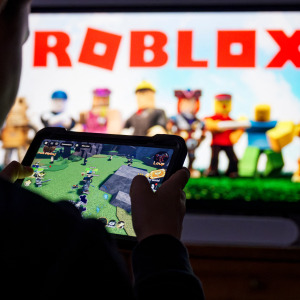 A child poses as he plays a video game on a tablet on Roblox.