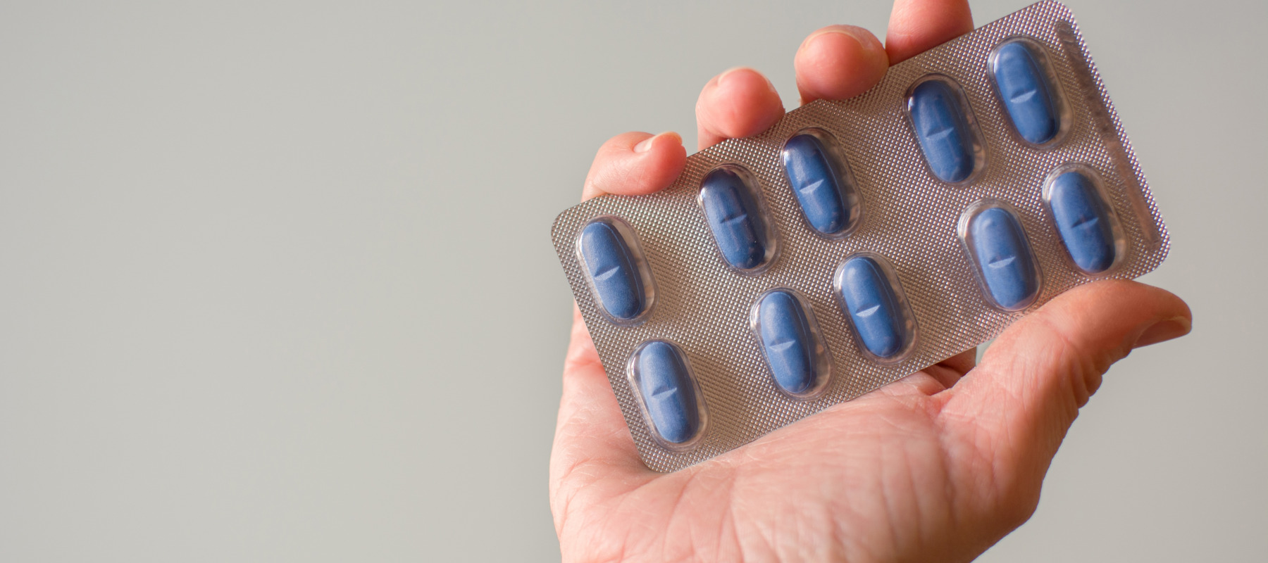Hand holding a back of blue pills