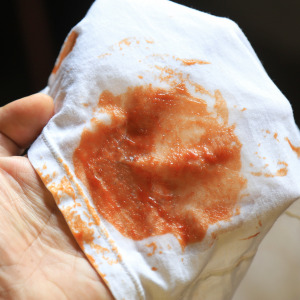 A split-panel photo of a couple eating spaghetti and a red sauce stain