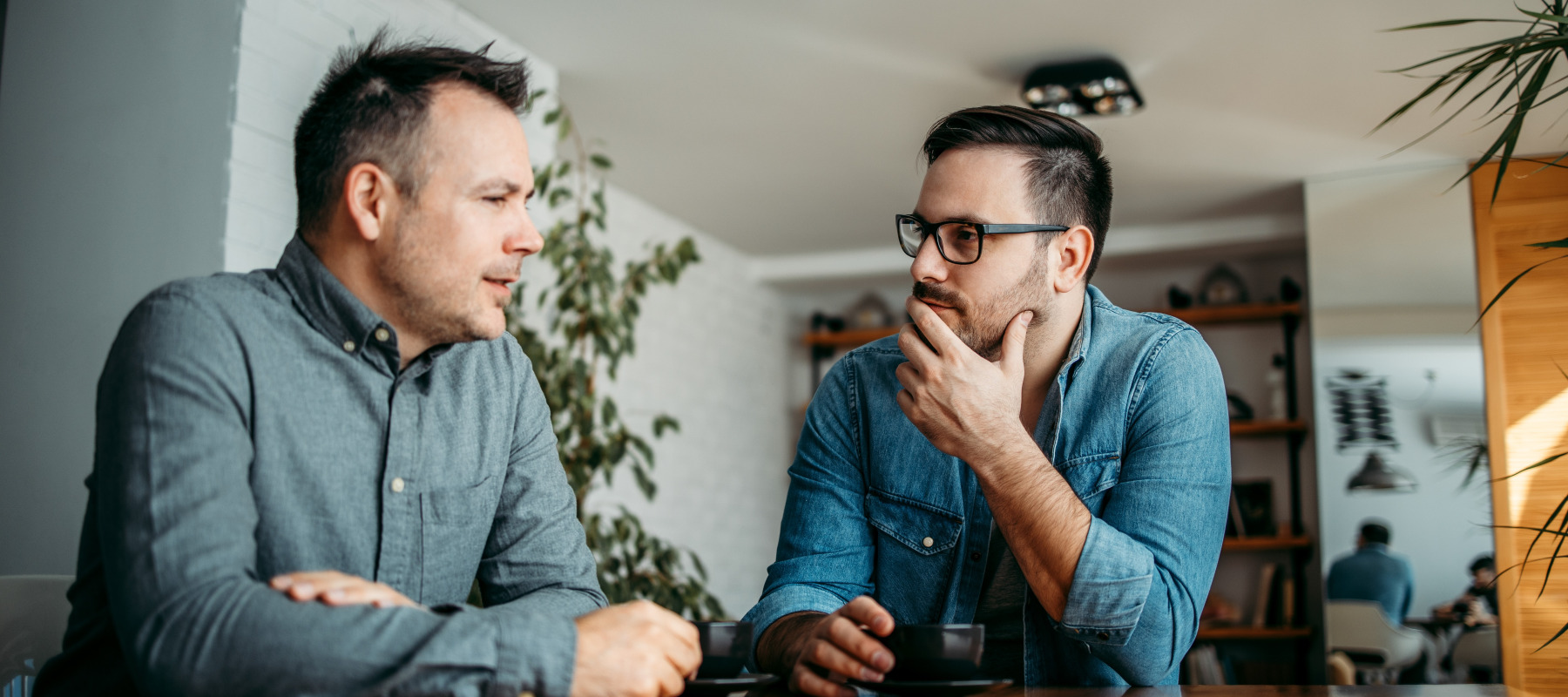 Two adult brothers have serious discussion at kitchen table