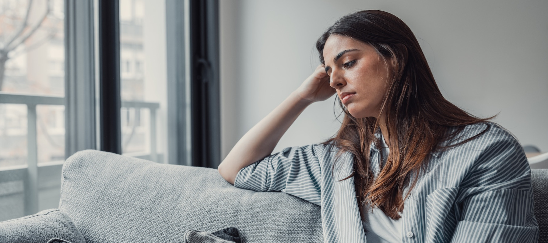Sad young woman sitting on a couch.